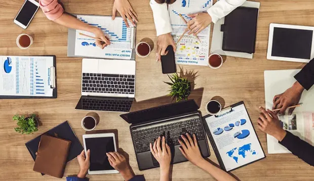 Top view of executive professionals in group meeting with laptop, coffee and document on a table